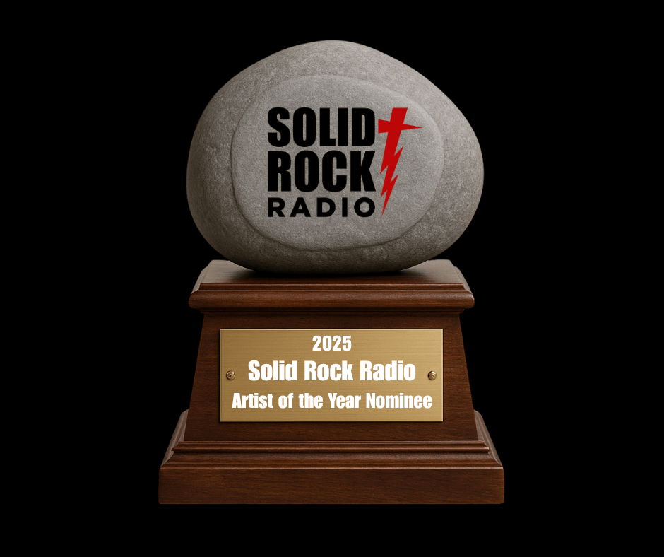 Image shows a wooden trophy base with a gold nameplate. The plate reads 2025 Solid Rock Radio Artist of the Year Nominee. A large smooth gray stone sits on top of the base. The stone displays the Solid Rock Radio logo with black text and a red lightning bolt shaped cross. The background is black.